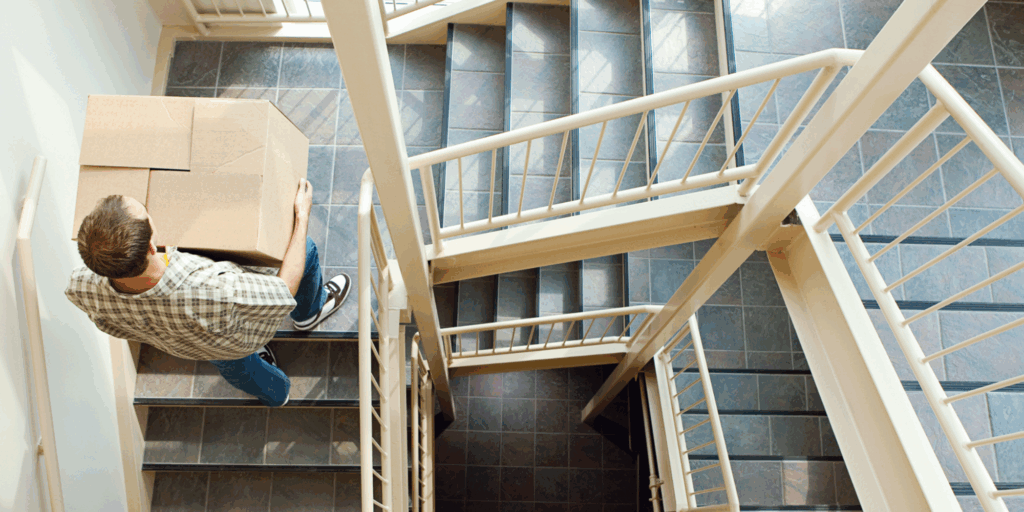 Man lifting box over multiple flights of stairs