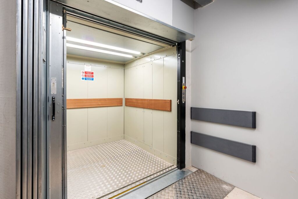 Heavy-duty goods lift features a robust steel cladding structure with protective epoxy finish, non-slip aluminium checker plate flooring and bump rails