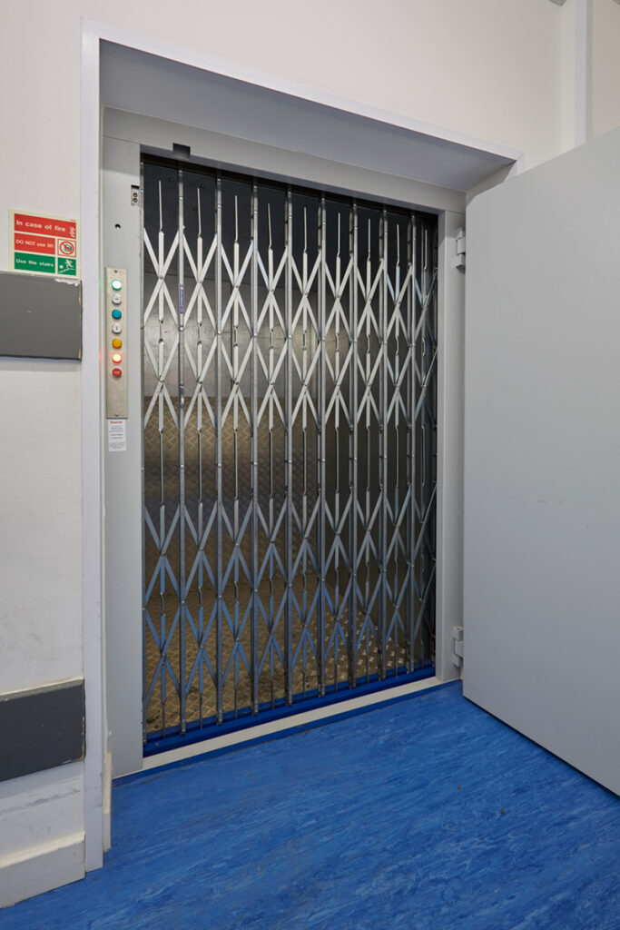 Collapsible stainless steel gates on a bespoke Goodsmaster in a retail environment.
