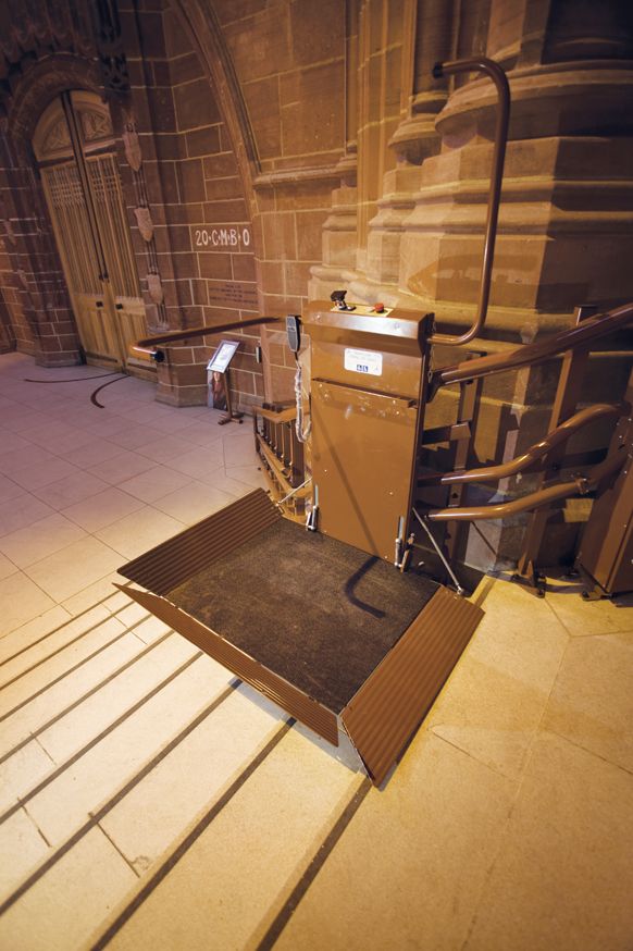 A Stairiser CR inclined platform lift in the Nave Well takes wheelchair-users up and down a curved stone staircase.