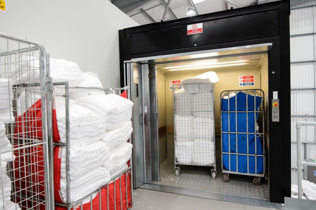 Roll cages inside 1000 kg Stannah Goodsmaster, CLEAN laundry in Slough