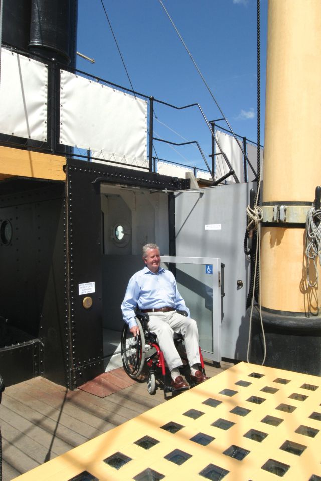 Lift passengers emerge onto the promenade deck , looking as if they have travelled through the funnel