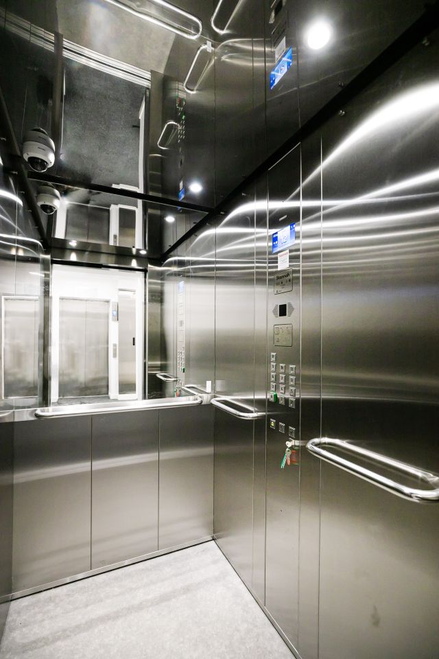 View of stainless steel passenger lift car interior with half-height mirror